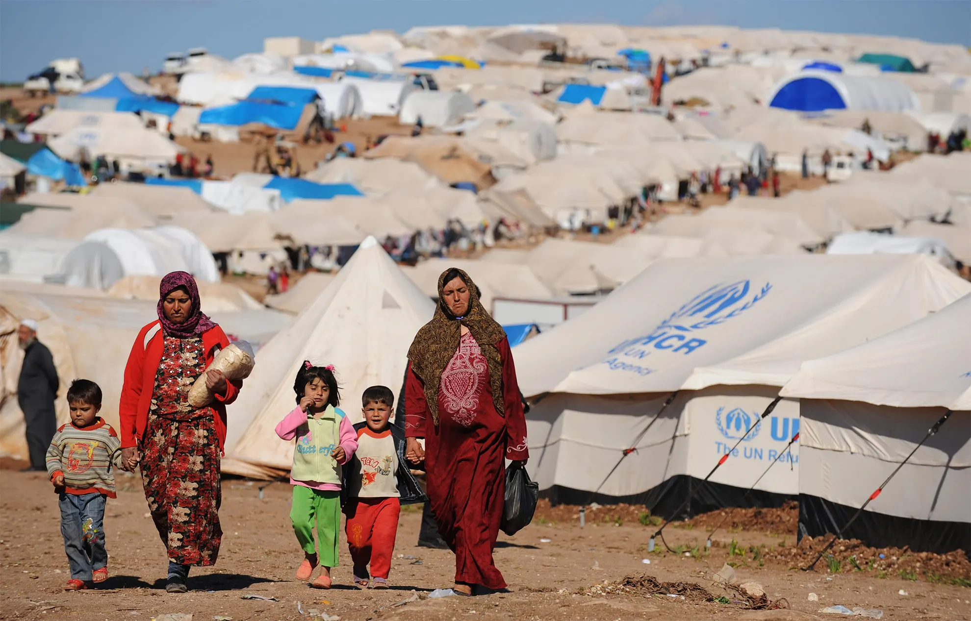 Refugiados caminhando por um acampamento das Nações Unidas