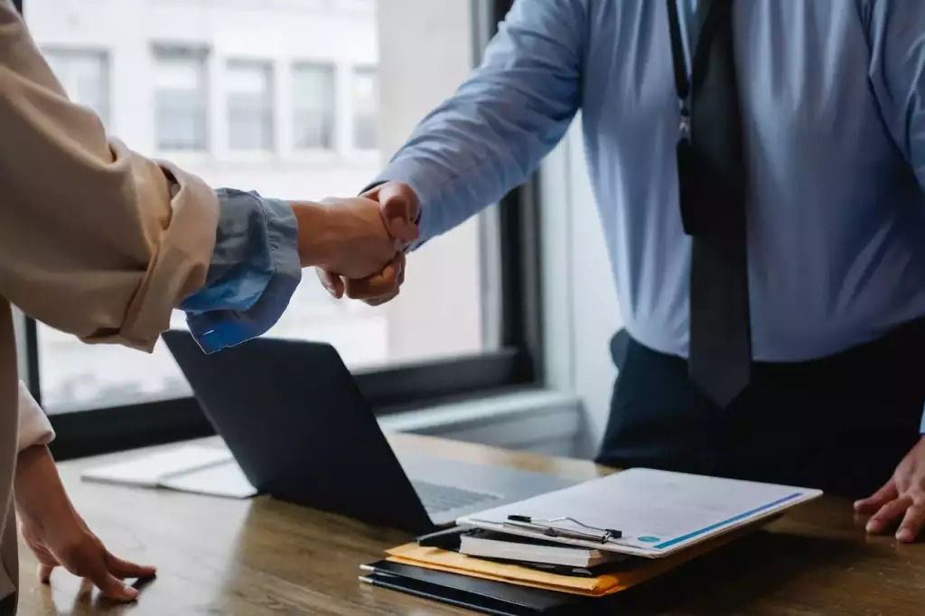 Empleador y empleado se dan la mano después de firmar contrato para un arraigo sociolaboral