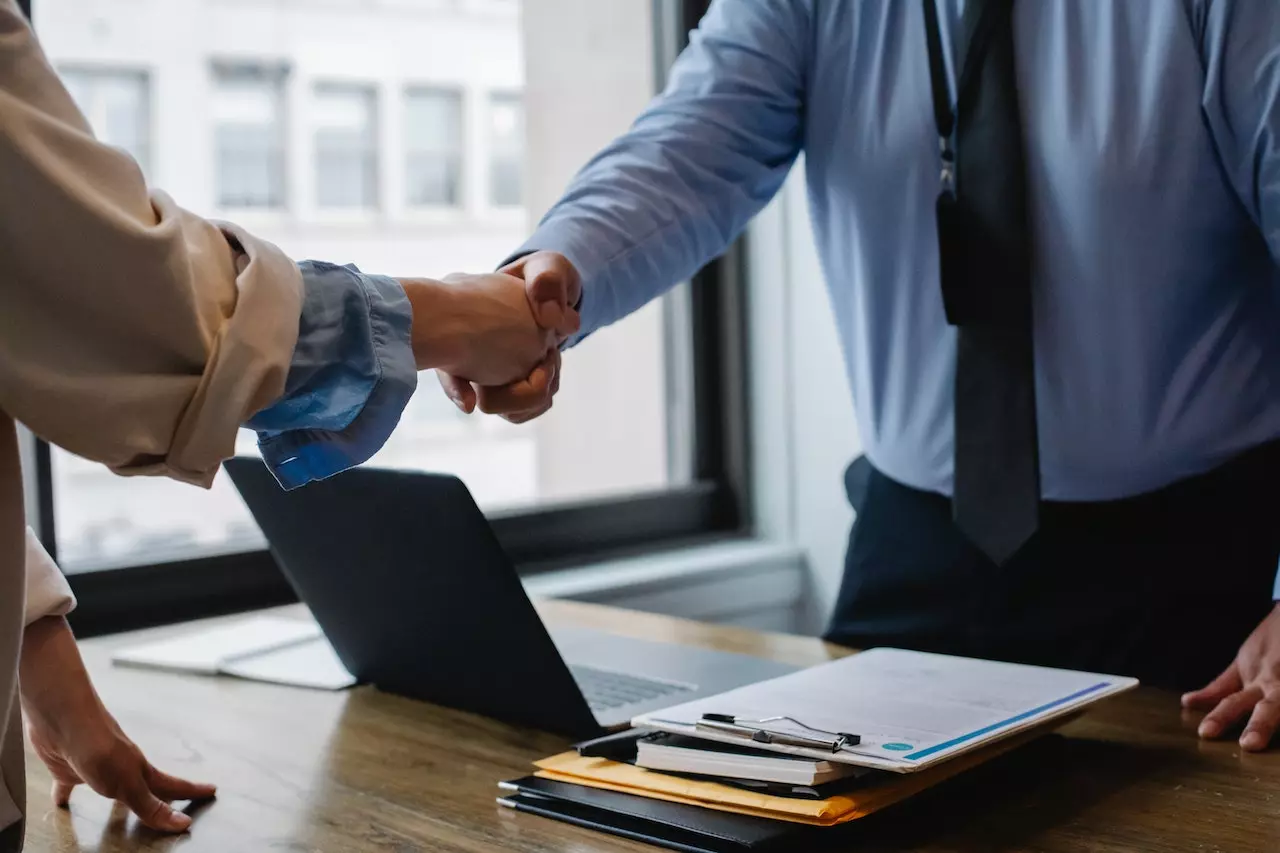 Empleador y empleado se dan la mano después de firmar contrato para un arraigo sociolaboral