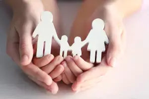Manos protectoras cuidando de una familia compuesta por padre, madre y dos niños