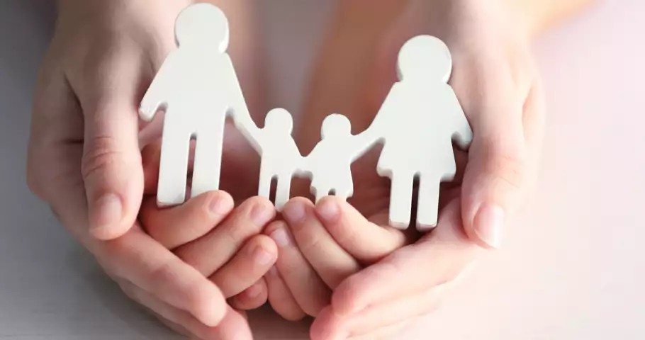 Manos protectoras cuidando de una familia compuesta por padre, madre y dos niños
