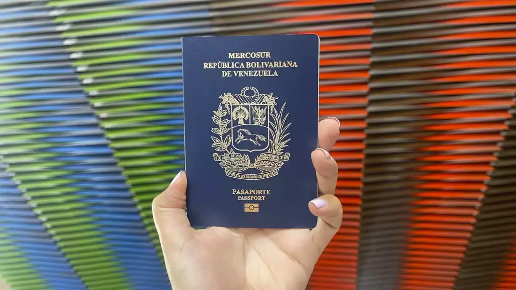 Una mano sostiene un pasaporte venezolano en un fondo de colores