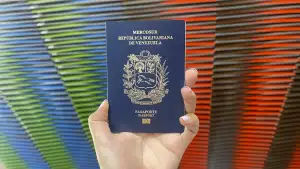 Una mano sostiene un pasaporte venezolano en un fondo de colores